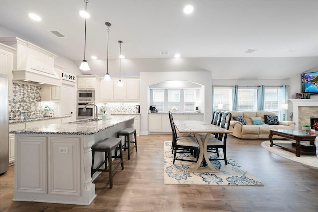 dining area featuring healthy amount of natural light, a lit fireplace, light wood-style floors, and recessed lighting
