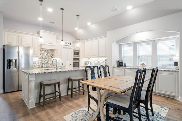 dining room with light wood finished floors, vaulted ceiling, and recessed lighting