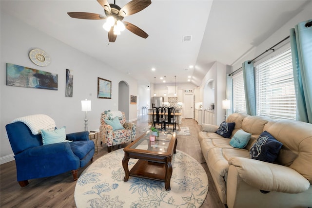 living room with arched walkways, wood finished floors, vaulted ceiling, ceiling fan, and baseboards