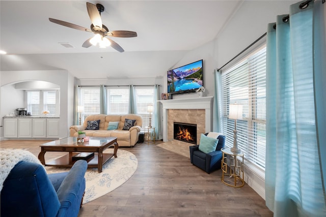 living room with a fireplace with flush hearth, lofted ceiling, wood finished floors, and a ceiling fan