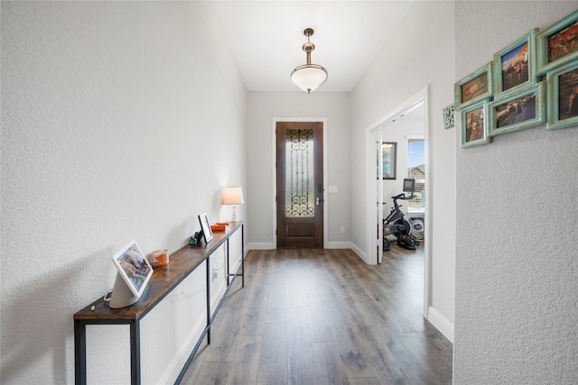 entryway featuring wood finished floors, baseboards, and a textured wall