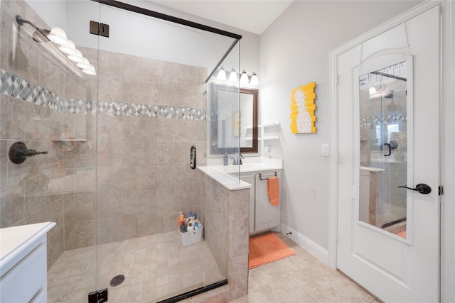 full bath with a stall shower, vanity, tile patterned flooring, and baseboards