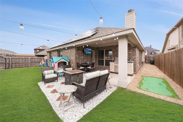 back of house with brick siding, a putting green, a chimney, and a patio area