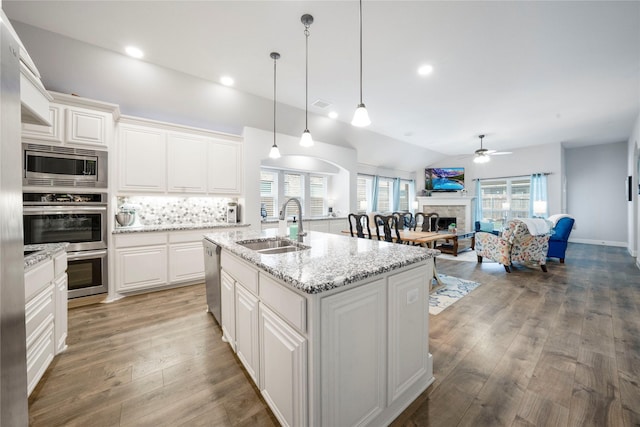 kitchen featuring a sink, stainless steel appliances, a fireplace, a ceiling fan, and open floor plan
