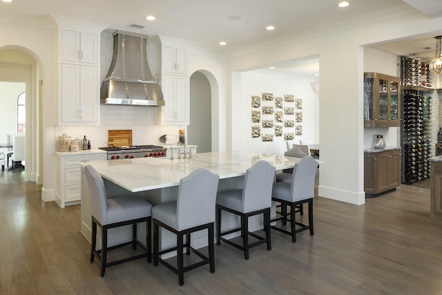 3205 Caruth Blvd, University Park, TX 75225 - kitchen with wall chimney exhaust hood, arched walkways, dark wood finished floors, ornamental molding, and recessed lighting