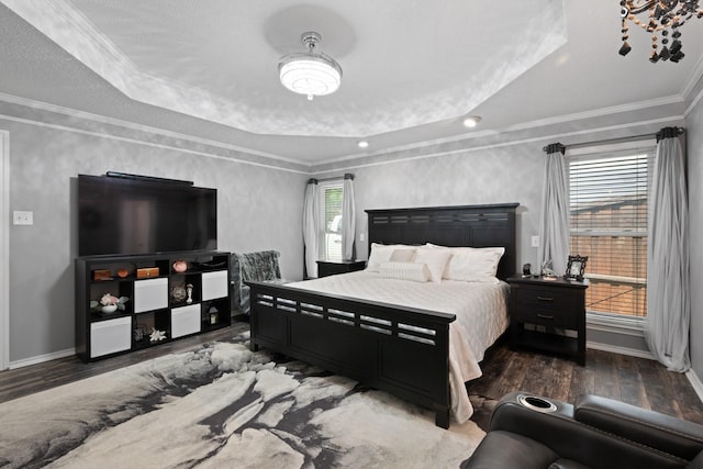 bedroom featuring a tray ceiling, wood finished floors, baseboards, and crown molding