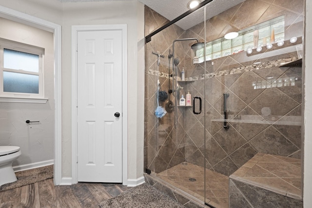 bathroom featuring a stall shower, toilet, and healthy amount of natural light