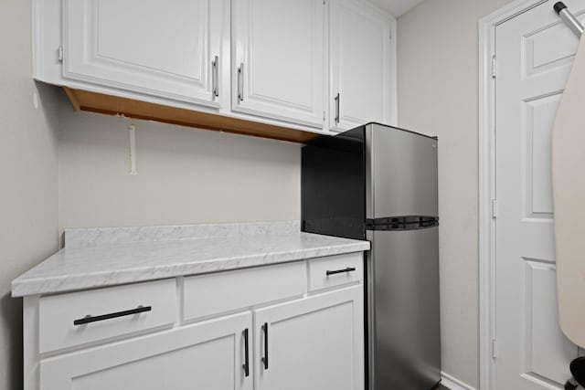 kitchen featuring white cabinetry and freestanding refrigerator