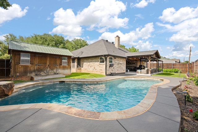 view of pool with a fenced backyard, an outdoor structure, and a patio area
