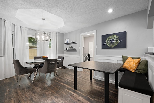 dining space with a textured ceiling, a chandelier, dark wood-style floors, washer / clothes dryer, and a wainscoted wall