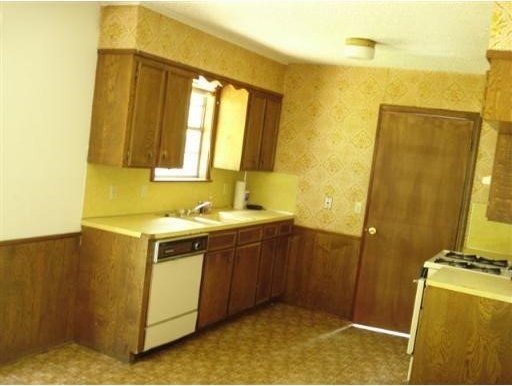 6334 Alameda, Shreveport, LA 71119 - kitchen with white dishwasher, brown cabinets, wallpapered walls, a wainscoted wall, and light countertops