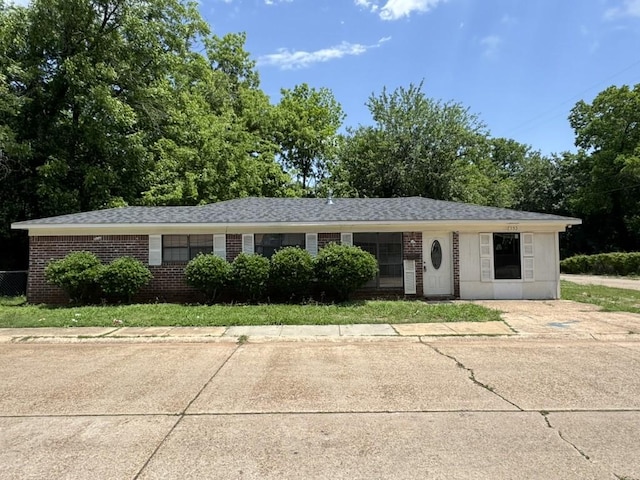 ranch-style house featuring brick siding and a shingled roof