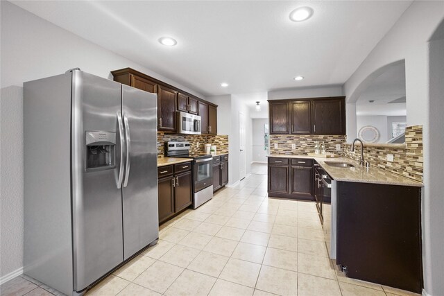 3513 San Lucas Ln, Denton, TX 76208 - kitchen featuring appliances with stainless steel finishes, a sink, dark brown cabinetry, tasteful backsplash, and recessed lighting
