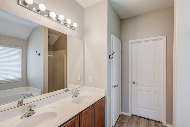 full bathroom featuring wood finished floors, double vanity, a shower stall, and a garden tub