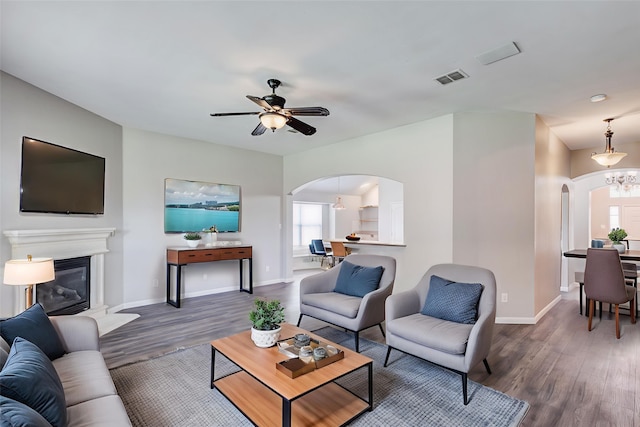 10310 Saint Georges Dr, Rowlett, TX 75089 - living area with arched walkways, wood finished floors, baseboards, a glass covered fireplace, and a ceiling fan