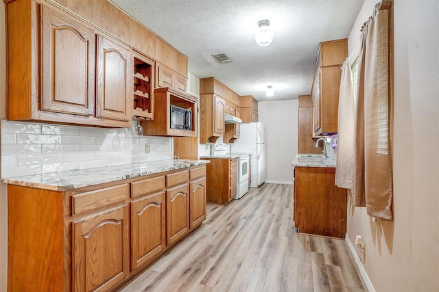 kitchen with a sink, black microwave, decorative backsplash, light wood-style floors, and white electric stove