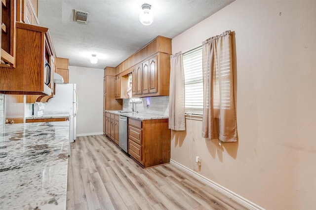 kitchen with baseboards, light wood-style floors, dishwasher, and a textured ceiling