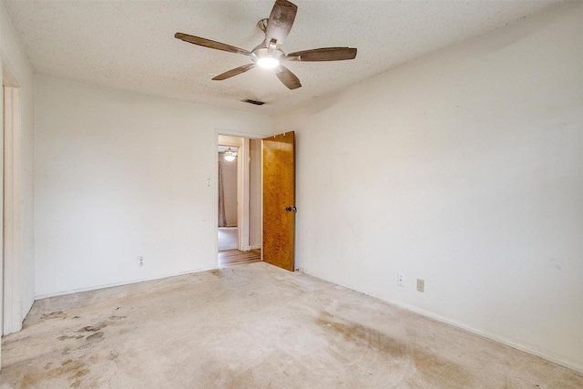 carpeted spare room with ceiling fan and a textured ceiling