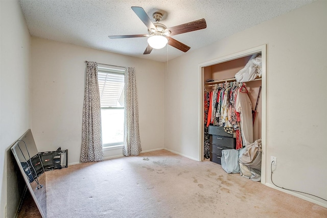 unfurnished bedroom featuring carpet, a textured ceiling, a closet, and a ceiling fan