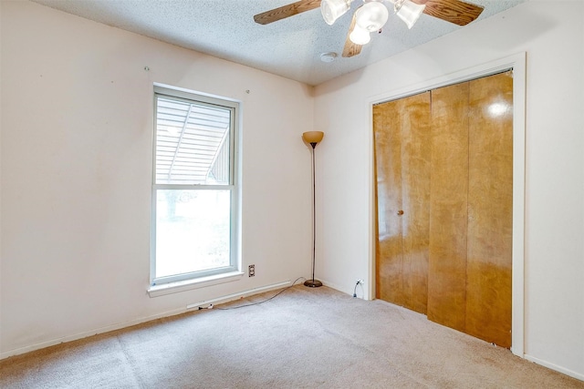 unfurnished bedroom with carpet floors, multiple windows, a textured ceiling, and a closet