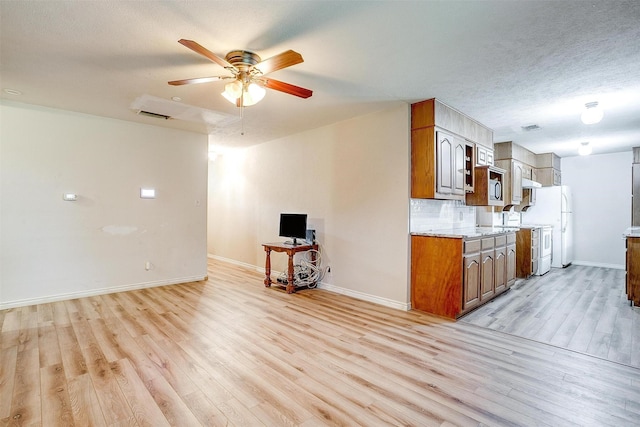 unfurnished living room with light wood-type flooring, ceiling fan, and baseboards