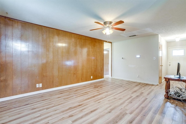 unfurnished living room featuring a ceiling fan, wood finished floors, and wood walls