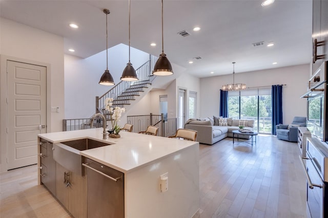 7704 Highcroft Way, Plano, TX 75024 - kitchen featuring a sink, appliances with stainless steel finishes, open floor plan, light wood finished floors, and a kitchen island with sink