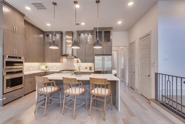 7704 Highcroft Way, Plano, TX 75024 - kitchen featuring stainless steel appliances, wall chimney exhaust hood, light wood-style flooring, decorative backsplash, and light countertops