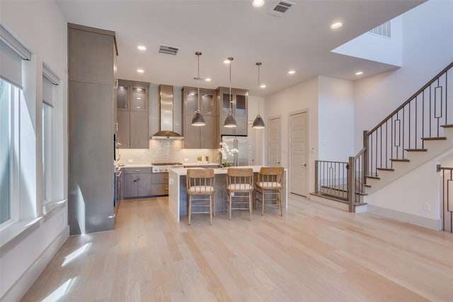 7704 Highcroft Way, Plano, TX 75024 - kitchen featuring wall chimney exhaust hood, light countertops, a kitchen bar, stainless steel built in refrigerator, and light wood-style flooring