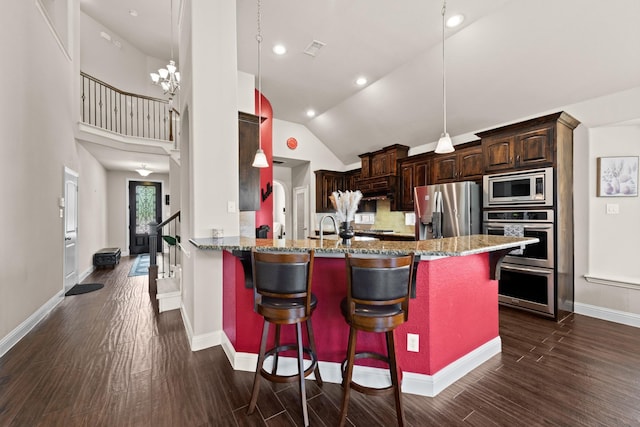 2444 Kingsgate Dr, Little Elm, TX 75068 - kitchen with appliances with stainless steel finishes, a kitchen breakfast bar, dark wood finished floors, baseboards, and vaulted ceiling