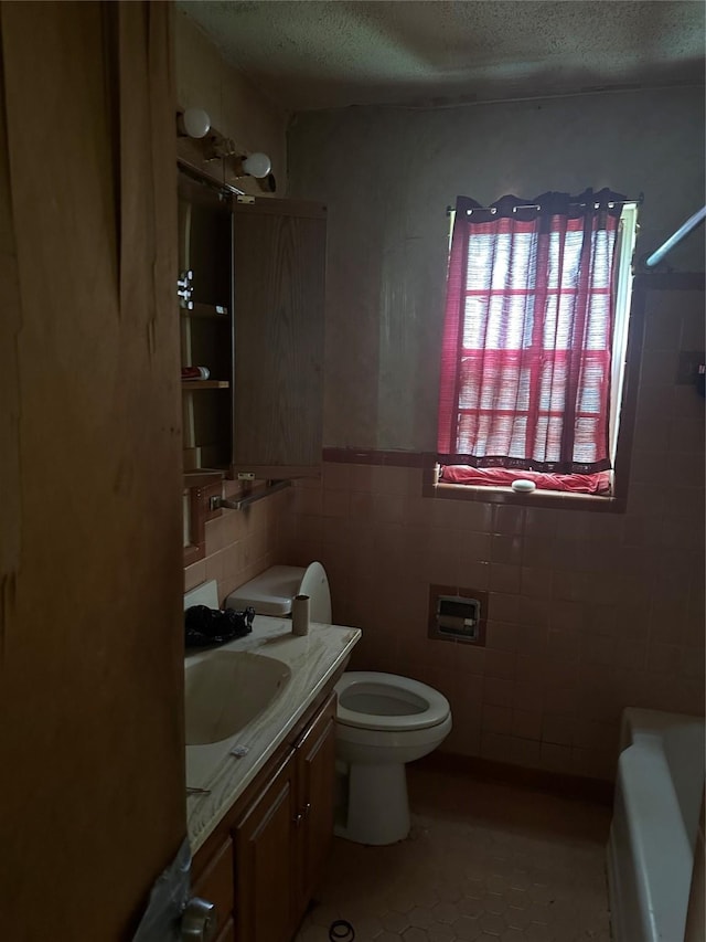 full bath featuring tile walls, toilet, a textured ceiling, vanity, and tile patterned floors