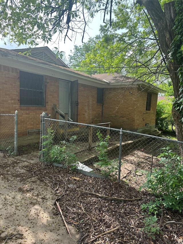 view of home's exterior featuring brick siding and fence