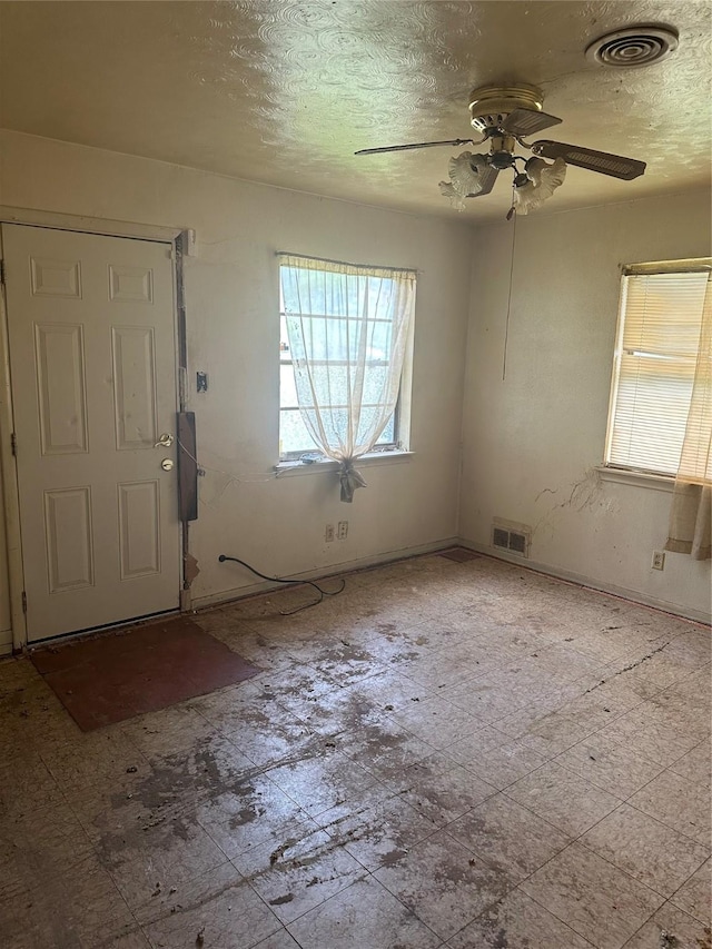 empty room with ceiling fan and a textured ceiling