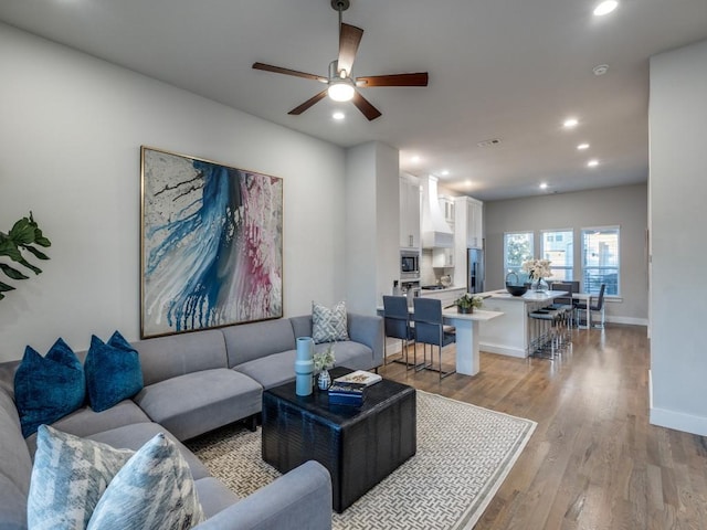 living area featuring light wood finished floors, recessed lighting, ceiling fan, and baseboards