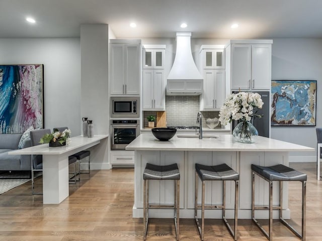 1129 Manderly Ct, Dallas, TX 75204 - kitchen with stainless steel appliances, premium range hood, a sink, a kitchen breakfast bar, and backsplash