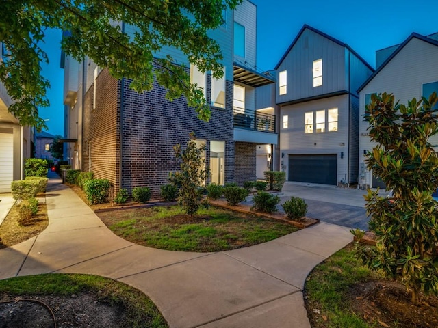 modern home featuring an attached garage, board and batten siding, concrete driveway, and brick siding