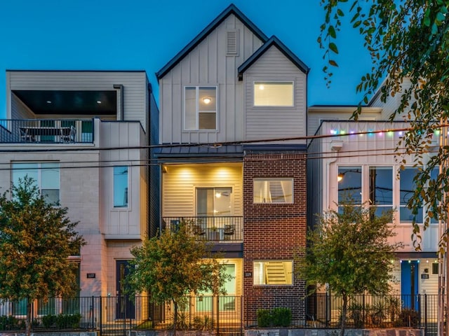 townhome / multi-family property with board and batten siding, a balcony, and brick siding