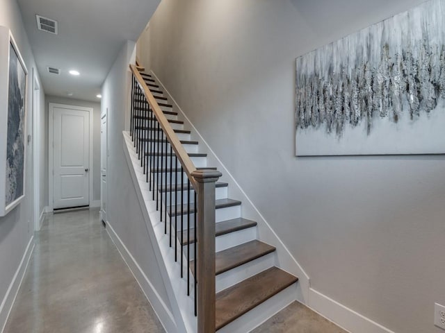 staircase featuring baseboards, finished concrete floors, and recessed lighting