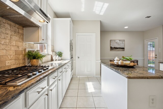 2805 Bitterroot Ct, Plano, TX 75025 - kitchen featuring wall chimney exhaust hood, appliances with stainless steel finishes, dark stone countertops, light tile patterned floors, and white cabinets