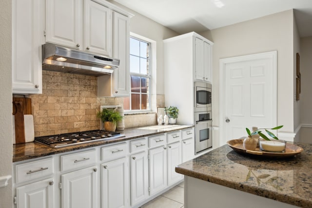 2805 Bitterroot Ct, Plano, TX 75025 - kitchen featuring under cabinet range hood, stainless steel appliances, white cabinets, dark stone counters, and backsplash