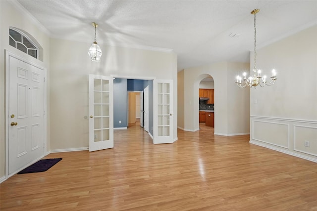 4416 Heath Ct, Plano, TX 75024 - foyer entrance with french doors, arched walkways, crown molding, light wood-style flooring, and a chandelier