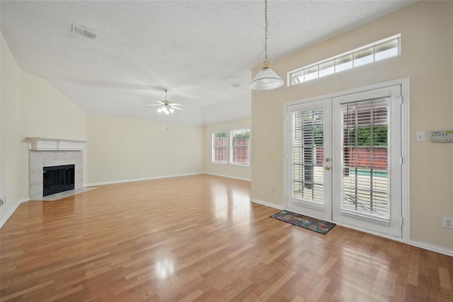 4416 Heath Ct, Plano, TX 75024 - unfurnished living room featuring a textured ceiling, light wood finished floors, a ceiling fan, french doors, and a tile fireplace