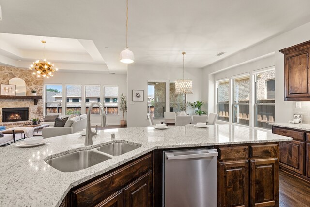 7020 Benjamin Way, Colleyville, TX 76034 - kitchen featuring stainless steel dishwasher, a chandelier, a stone fireplace, and plenty of natural light