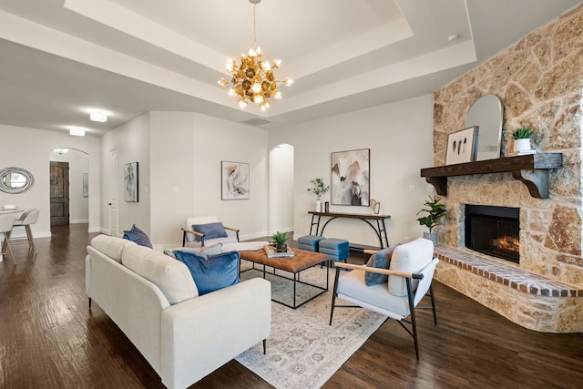 7020 Benjamin Way, Colleyville, TX 76034 - living room featuring arched walkways, a chandelier, wood finished floors, a tray ceiling, and a large fireplace