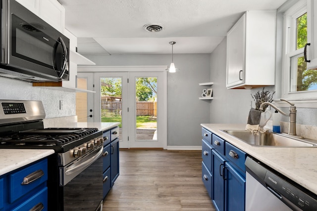 723 Westover Dr, Richardson, TX 75080 - kitchen with blue cabinetry, stainless steel appliances, a sink, wood finished floors, and white cabinets