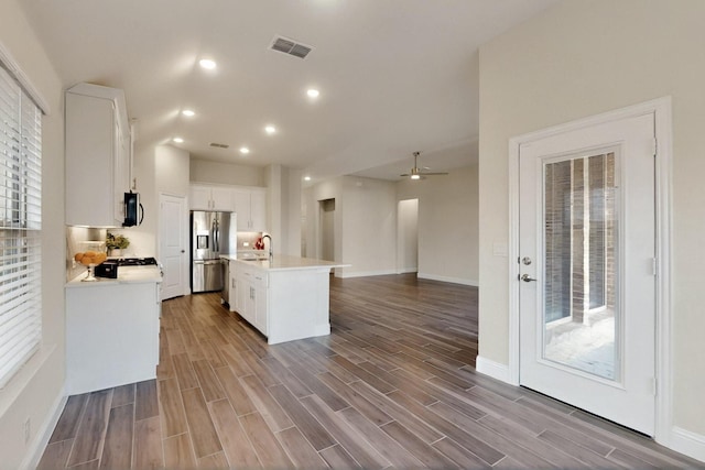 kitchen with stainless steel appliances, light countertops, an island with sink, white cabinetry, and wood finished floors