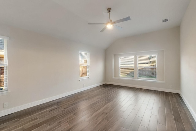 spare room with healthy amount of natural light, ceiling fan, dark wood-style flooring, lofted ceiling, and baseboards