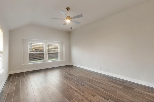 empty room with healthy amount of natural light, dark wood-type flooring, ceiling fan, baseboards, and vaulted ceiling