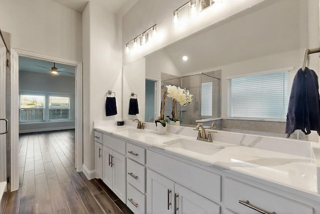 full bath with a stall shower, a ceiling fan, double vanity, wood finished floors, and vaulted ceiling