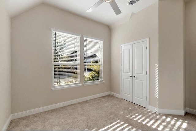 unfurnished bedroom featuring carpet flooring, lofted ceiling, baseboards, a closet, and ceiling fan